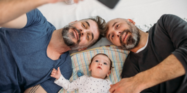 Two middle aged men taking a selfie with their baby